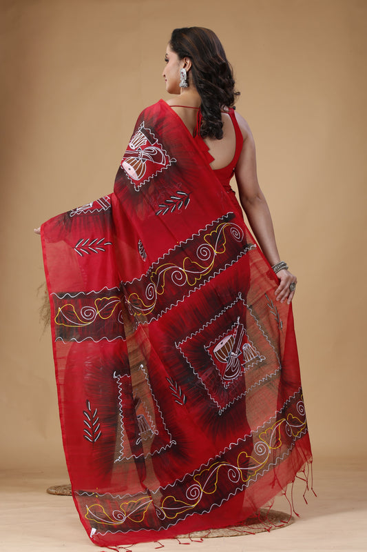Woman wearing a red saree with intricate patterns on a beige background