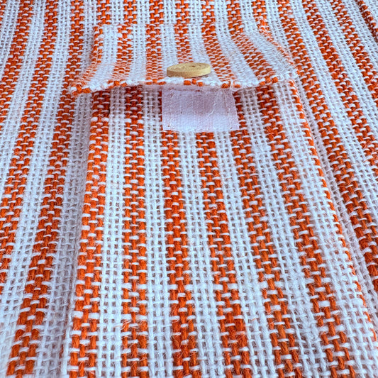 Close-up of orange and white striped fabric with a visible brand label.