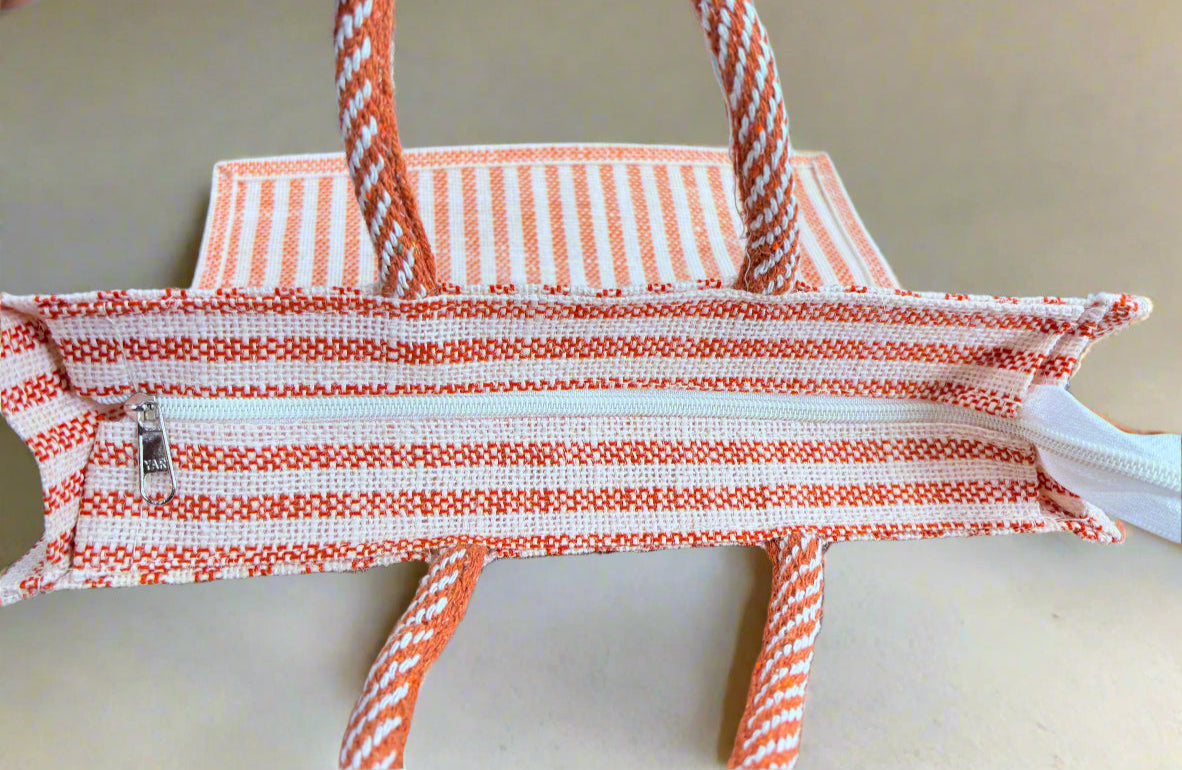 Orange and white striped bag with a zipper on a wooden surface.