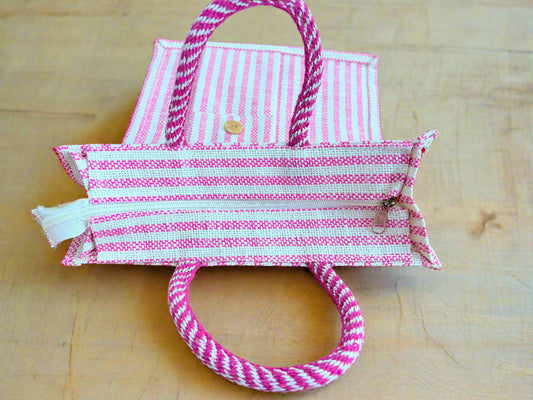 Pink and white striped bag with handles on a wooden surface