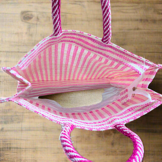 Pink striped bag on a reflective surface with decorative items in the background