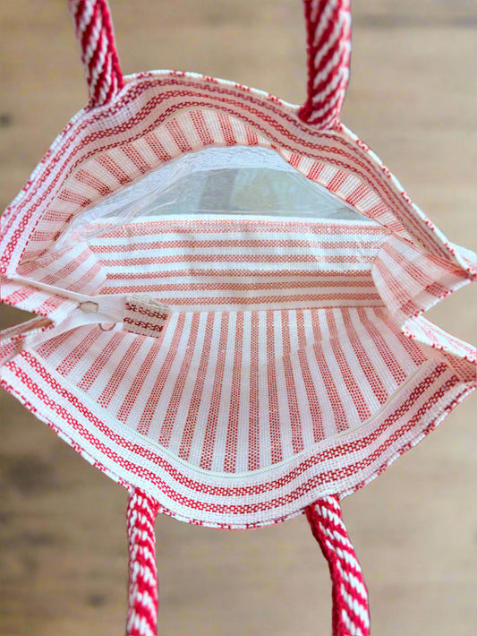 Small red and white striped bag with handles on a blurred background